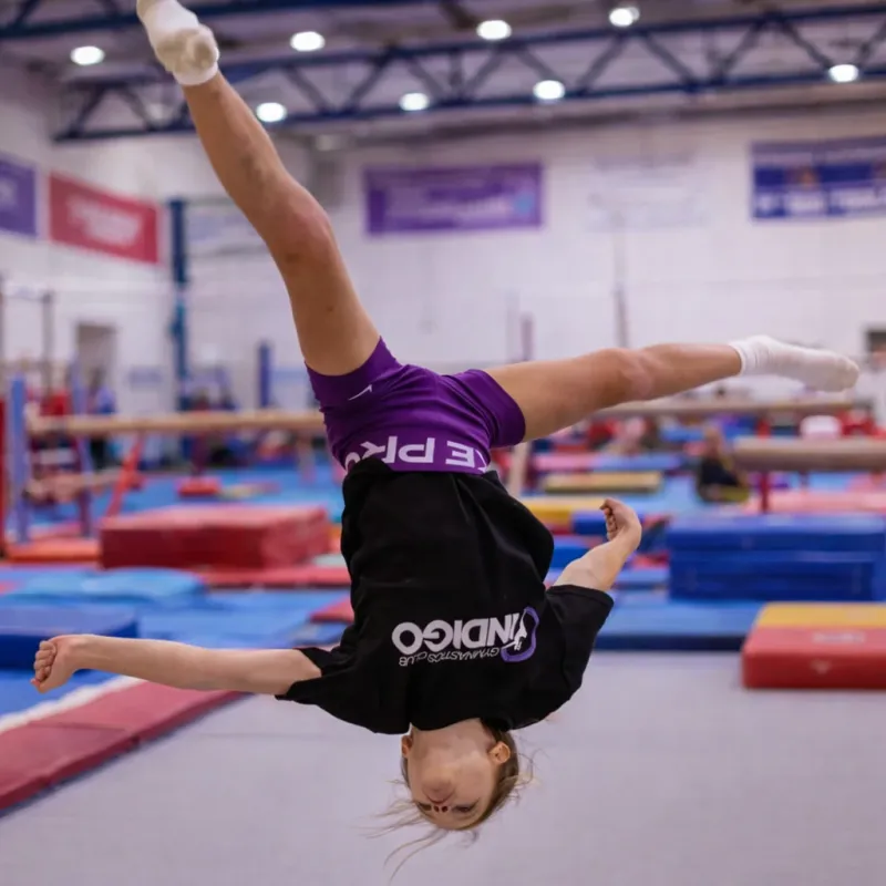 An advanced gymnast performing a mid-air flip at Pennine Gymnastics Club.